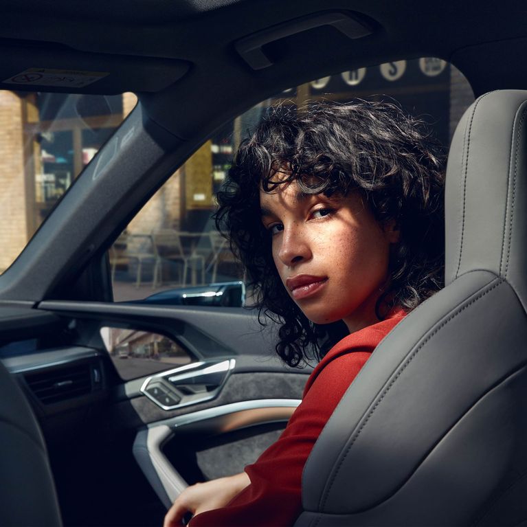 Woman looks back over her shoulder from the passenger seat of an Audi e-tron Sportback