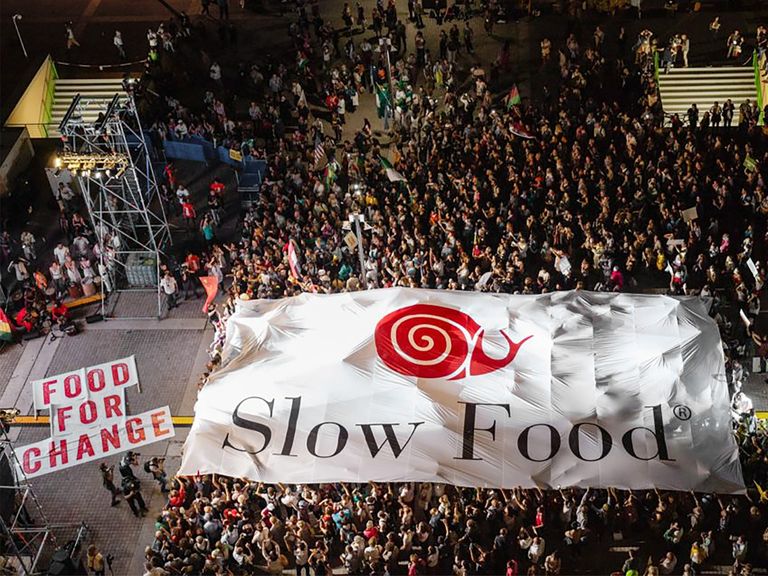 Une foule se tient devant une scène brandissant une immense banderole Slow Food