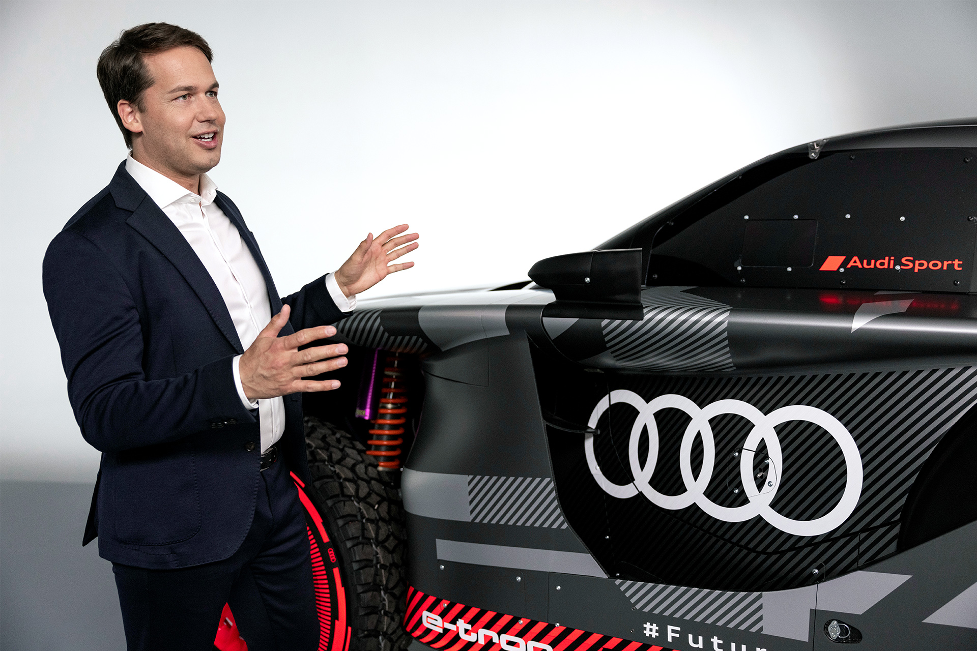 Julius Seebach parle avec les mains en se tenant à côté de l'Audi RS Q e-tron.